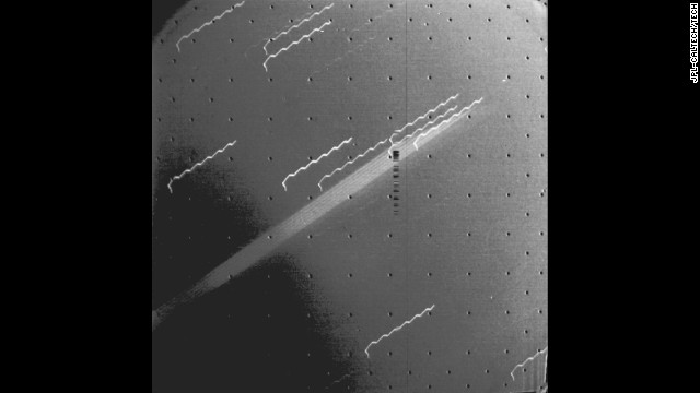 Voyager 1 captured the first evidence of a ring around the planet Jupiter. The multiple exposure of the extremely thin faint ring appears as a broad light band crossing the center of the picture. The background stars look like broken hairpins because of spacecraft motion during the 11-minute exposure. The black dots are geometric calibration points in the camera.