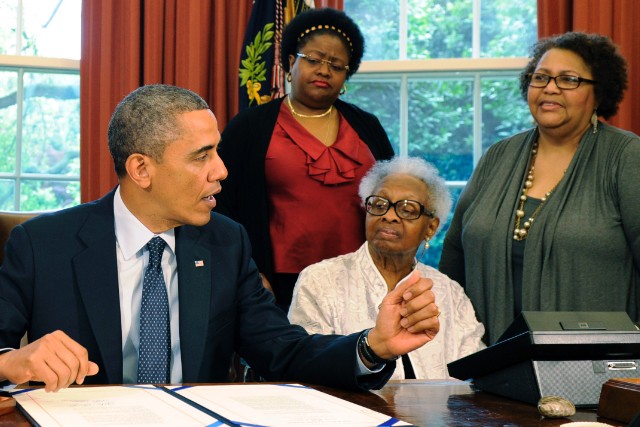 Lisa and Maxine McNair, Dianne Robertson Braddock (L-R) watch the president approve posthumous medals.