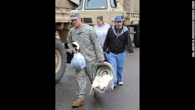 Colorado Army National Guard Sgt. David Wilson carries Ezra Villa while escorting Thomas Walter and Melinda Villa to the flood evaluation area in Lyons, Colorado, on September 13, 2013.