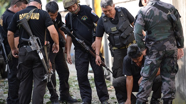 Members of Philippine police and military bomb squads look for evidence next to a destroyed car after a suspected car bomb explosion amidst heavy firefight between government troops and Muslim rebels on September 16, 2013.