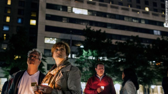 Gordon Morris, left, and wife Laura watch as flags are lowered to half-staff during the vigil at Freedom Plaza.