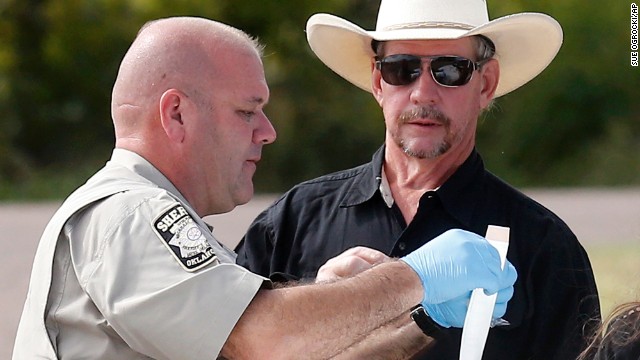 Tim Porter, right, talks with Beckham County Sheriff's Deputy J. Kessel, after giving a DNA sample at the scene on September 18, 2013. Porter says he believes his grandfather's remains may be in one of the cars.