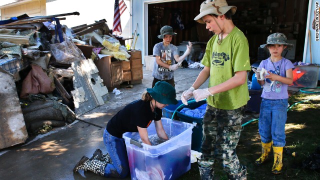 From left, siblings Elizabeth, 13, Jonathan, 9, Aaron, 11, and Kitty Dipert, 6, wash mud from the clothing of family friends from church on September 18 in Longmont, Colorado.