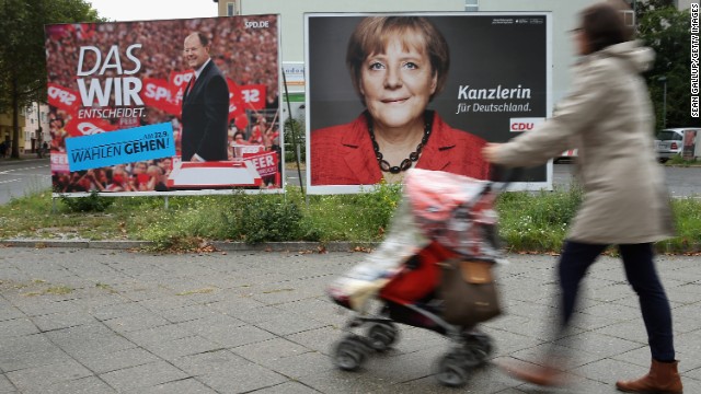 A woman pushes a stroller past election campaign posters for Angela Merkel and Peer Steinbrueck on September 16, 2013 in Berlin, Germany.