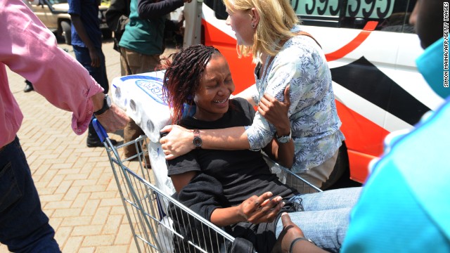 A woman is pulled by a shopping cart to an ambulance.