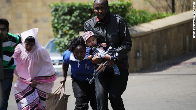 A policeman carries a baby to safety. Authorities said multiple shooters were at the scene. 