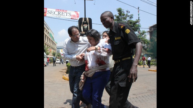 A security officer helps a wounded woman outside. 