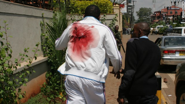 A wounded man is escorted outside the mall. 