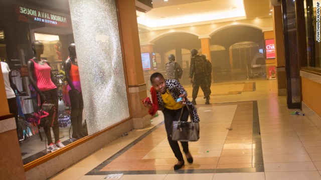 A woman who had been hiding during the attack runs for cover after armed police enter the mall. 