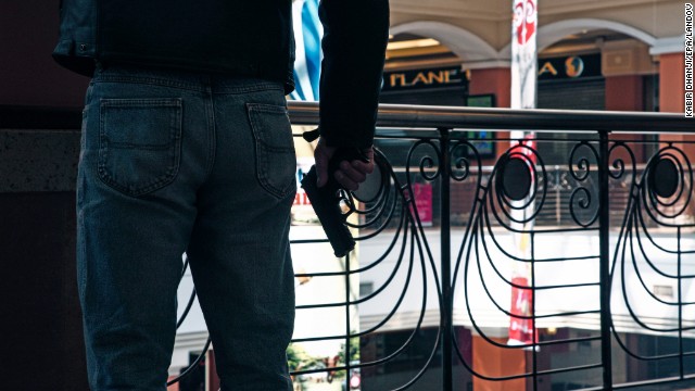 An armed official takes a shooting position inside the mall.