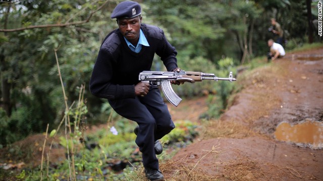 A Kenyan police security officer runs for cover as heavy smoke rises from the mall on September 23.