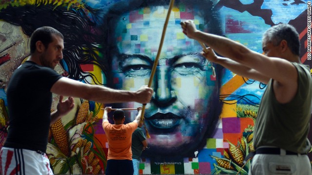 People train stick fight in front of a mural depicting late Venezuelan former President Hugo Chavez, August, 18, 2013. 