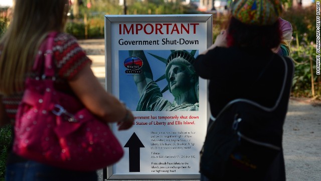 People look at a sign announcing that the Statue of Liberty is closed in New York on October 1.