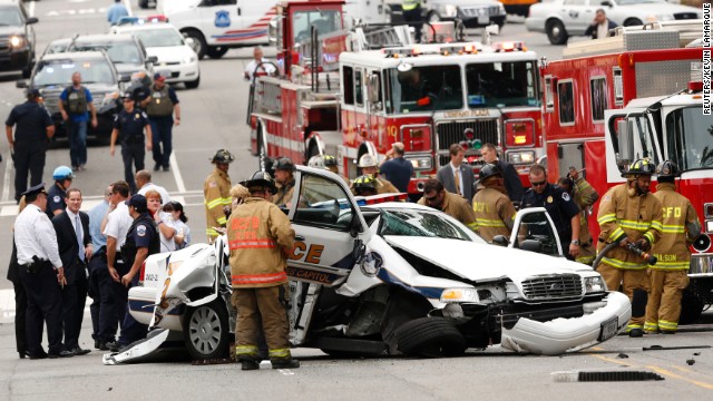 Rescue personnel stand around a smashed U.S. Capitol Police cruiser near the Capitol.