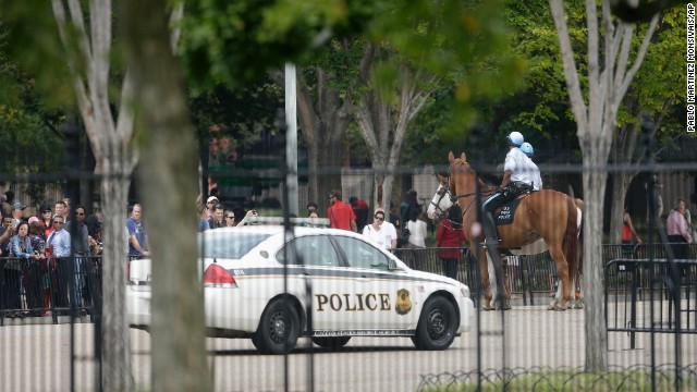 A Secret Service vehicle joins law enforcement officers riding on horseback.