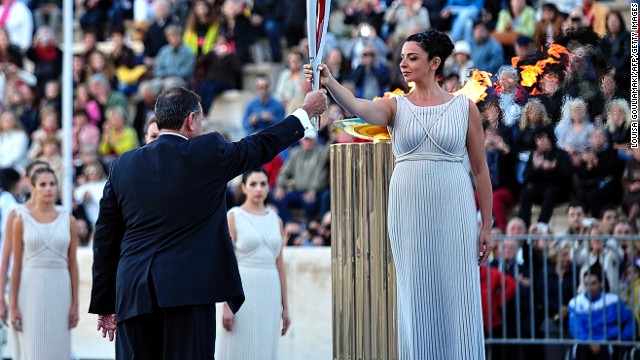 Actress Ino Menegaki, playing a high priestess, hands the Olympic flame to the president of the Hellenic Olympic Committee, Spyros Kapralos, at the Panathenaic stadium in Athens.