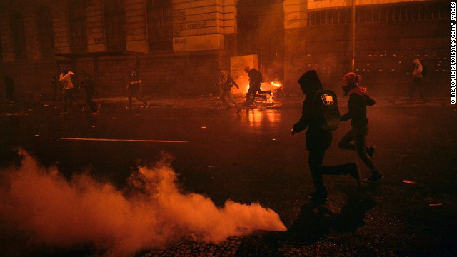 Demonstrators run after riot police used tear gas to disperse the crowds during the October 7 Rio protests.