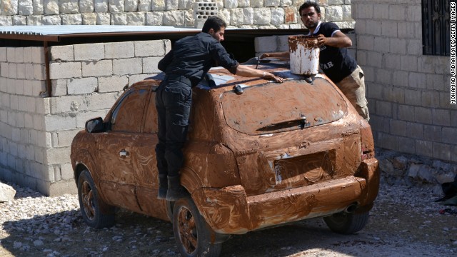 Rebel fighters cover a car in mud for camouflage at an undisclosed location in Syria's northwestern province of Idlib on Tuesday, October 8.