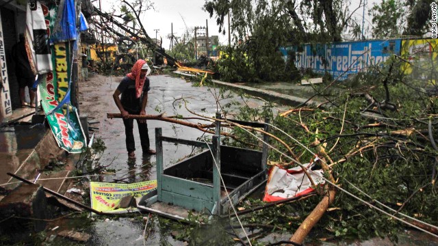 An man salvages a table stuck in uprooted trees fallen during the storm on a road in Berhampur on October 13.