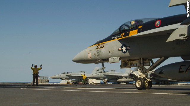 Landing Signal Officer guides in a fighter jet on the deck of the USS George Washington. The Naval Institute categorizes the Nimitz-class ship as a 'super carrier.' 