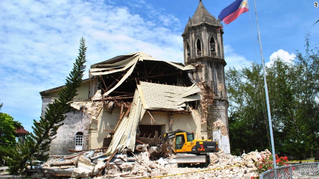 A crane sifts through the rubble of Our Lady of Assumption Parish Church in Dauis on October 15.