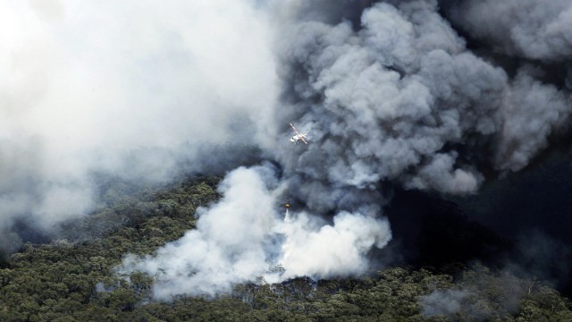A helicopter works to extinguish bush fires burning near Winmalee on October 18.