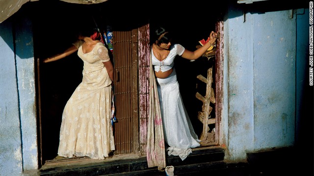 Jodi Cobb joined National Geographic as one of the magazine's first female staff photographers, in 1977. In this image she captures prostitutes, who are known as cage girls and are often sex slaves, displaying themselves on a Mumbai street.