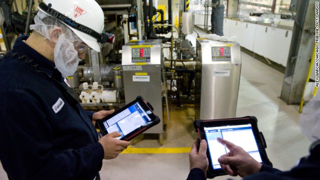 Technician Grimaldo Romero, left, uses his iPad to help maintain machinery at the World's Finest Chocolate plant in Chicago, Illinois, on March 21, 2013.