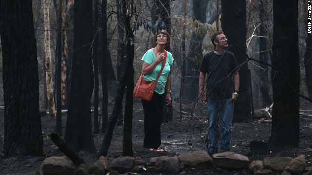 People walk around the area behind their destroyed home in Winmalee on October 22.