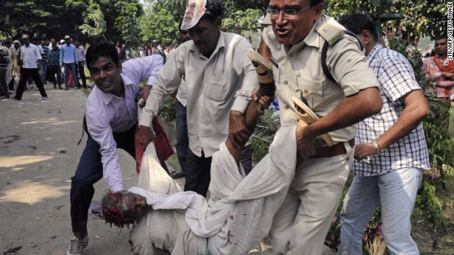 An Indian police officer and bystanders help an injured man when a series of bombs went off before a political rally.