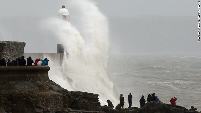 People watch as large waves break against barriers at the harbor in Porthcawl, Wales, on Sunday. 