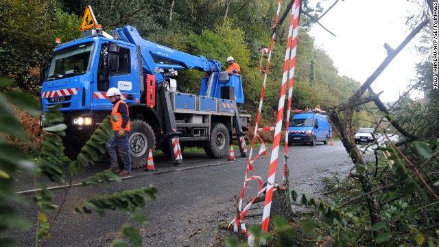 Electric company workers cut tree branches and repair power lines Monday in La Roche-Maurice, France. Officials said early Monday that 42,000 homes in northern France were without electricity.