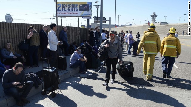 Passengers wait on the curb after leaving the airport.