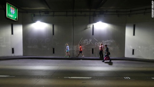 A family walks through a tunnel as they leave the airport. 