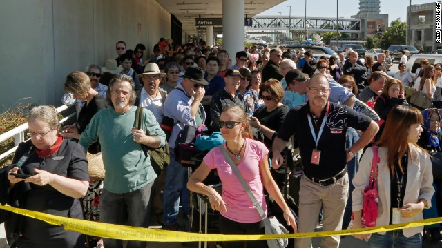 Passengers evacuated from Terminal 1 wait outside the airport. 