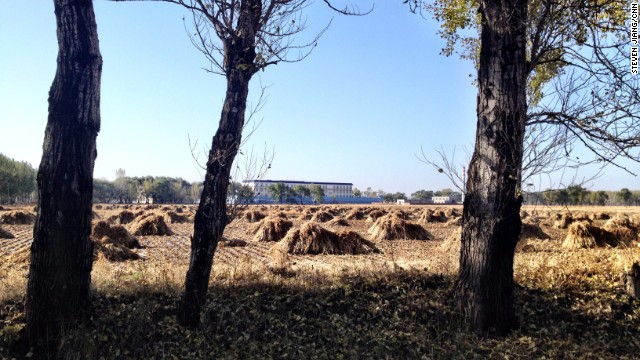 The male inmates' quarters at the Masanjia labor camp stand behind fields covered in haystacks.