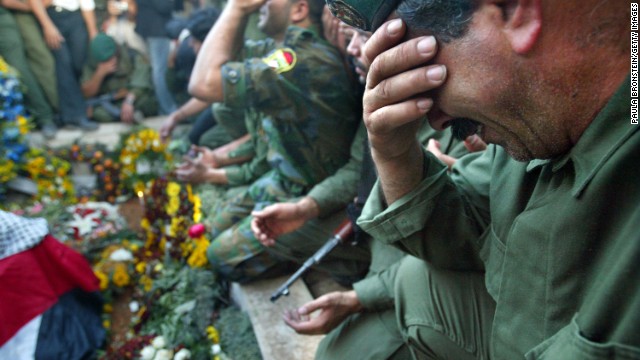 Palestinian security forces cry over Arafat's grave after he was buried at his compound in Ramallah on November 12, 2004.