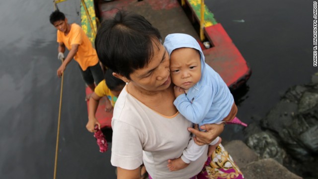 A woman carries a baby across a river November 8 at a coastal village in Las Pinas, Philippines.