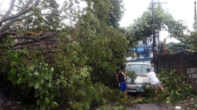 Residents clear a road November 8 after a tree was toppled by strong winds in the Philippine province of Cebu.