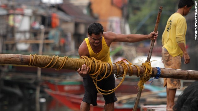 A fisherman lifts a post to reinforce his home at a coastal village in Las Pinas on November 8.