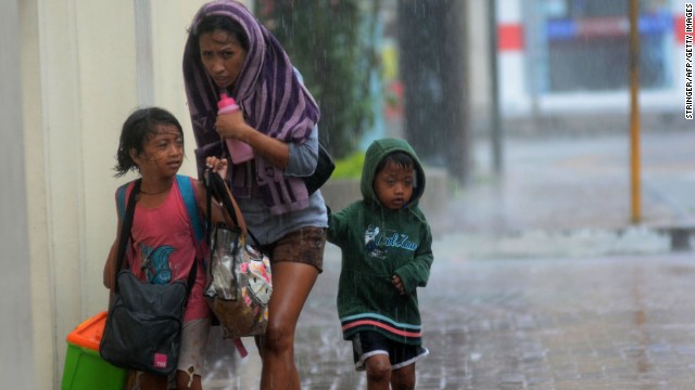 A woman and her children head for an evacuation center November 8 amid strong winds in Cebu City, Philippines.