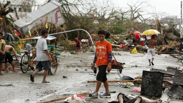 People walk past a victim left on the side of a road in Tacloban.