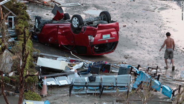 A resident passes an overturned car in Tacloban on November 9.