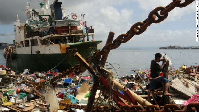 A man searches through debris next to a ship washed ashore in the devastated city of Tacloban, Philippines, on Sunday, November 10. The most powerful cyclone in three decades battered the Philippines, killing hundreds of people and leaving more than 100 bodies scattered on the streets of this coastal city.