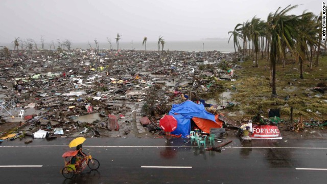 People ride past destruction in Tacloban on Sunday, November 10.