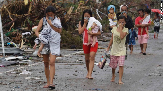 People cover their noses to block the smell of bodies in Tacloban on November 10.