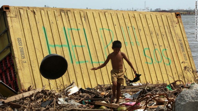 A boy in Tacloban walks near a container appealing for help.