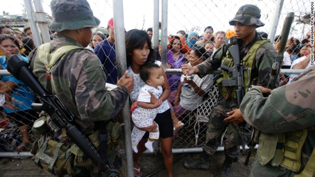 Soldiers let a woman and her child through a fence to get food November 11 outside the Tacloban airport.