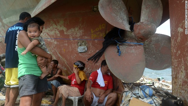 Residents of Anibong, Philippines, rest November 11 near a ship propeller that washed ashore during the storm.