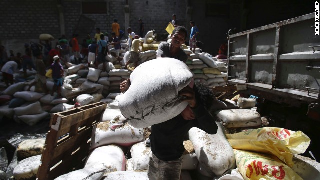 Residents carry bags of rice from a Tacloban warehouse that they stormed November 11 because of a food shortage.